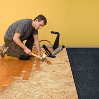 A man using an electric hammer to cut the floor.
